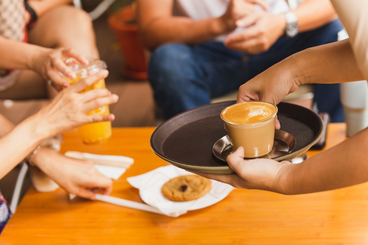 A Malaysian F&B staff serving coffee to his customers