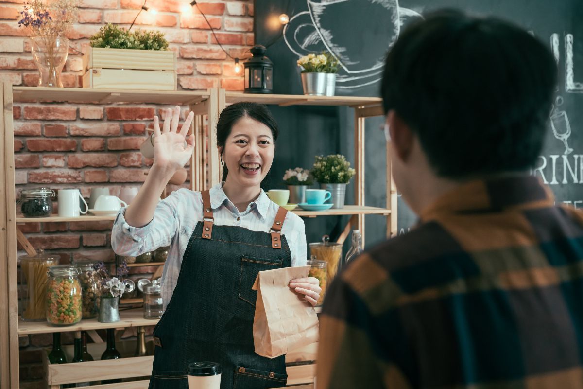 A Malaysian business owner waving goodbye to her customer after offering him a loyalty program