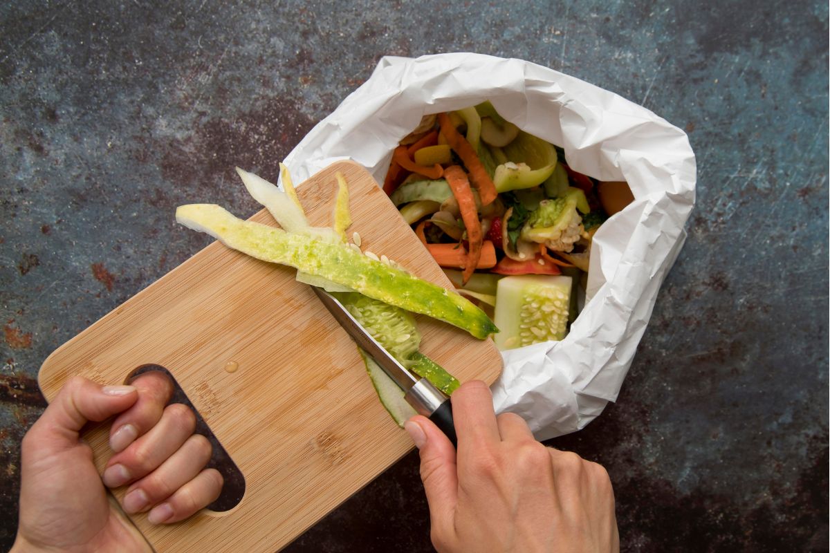 Restaurant chef throwing away food scraps into a bin