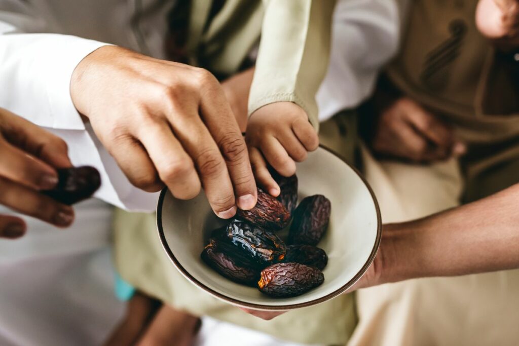 Hands reaching out to a bowl of dates