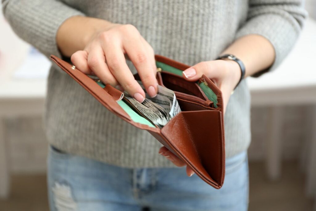 a woman opening his brown wallet