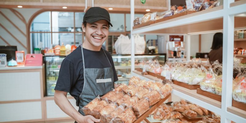 A bakery employee smiling while holding pastries