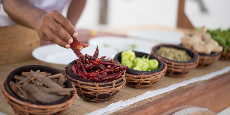 A person preparing food with different spices