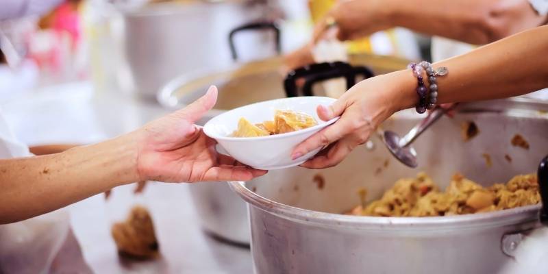 A bowl of food being handed over to another person