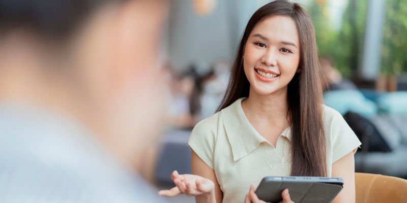 A woman holding an iPad explaining to someone