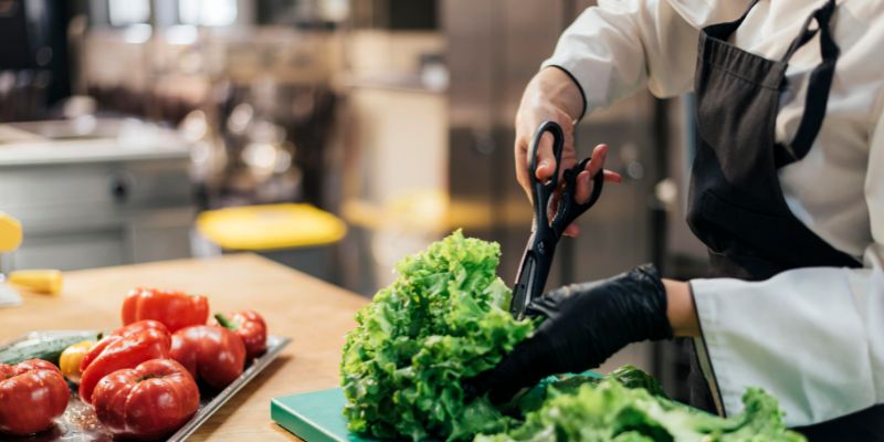 A chef cutting some leafy vegetables in the kitchen