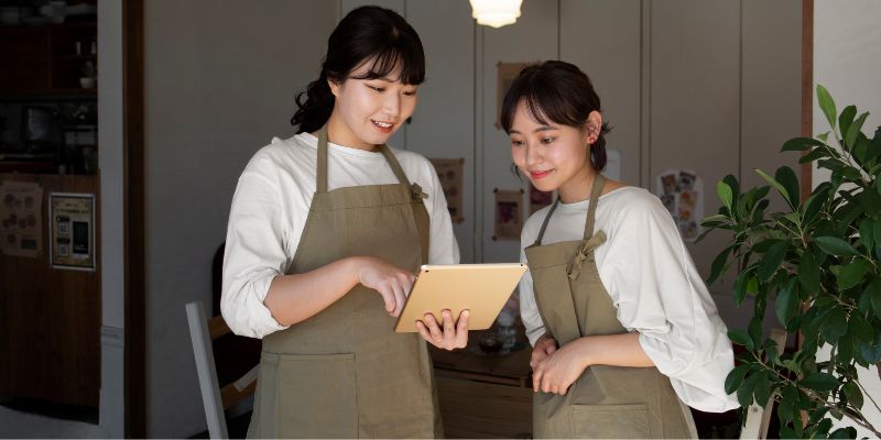 Two waitresses looking at a tablet while discussing