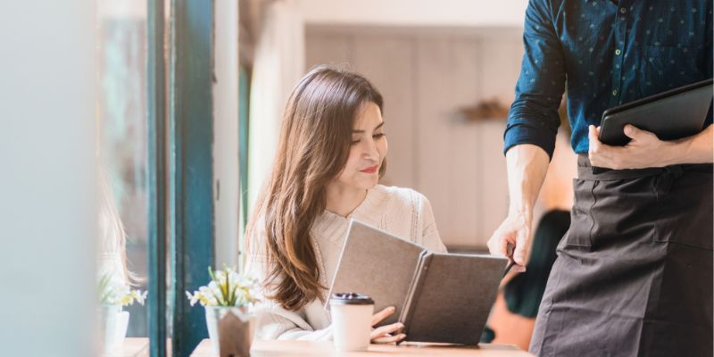 Waiter pointing at a menu the customer is holding