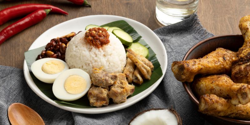 A plate of nasi lemak with fried chicken on the side