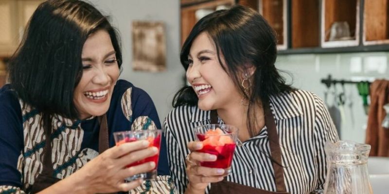 Two women laughing while holding a cold drink