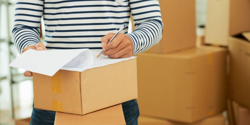 Mid-section of man in striped long sleeve shirt filling out the form on the box