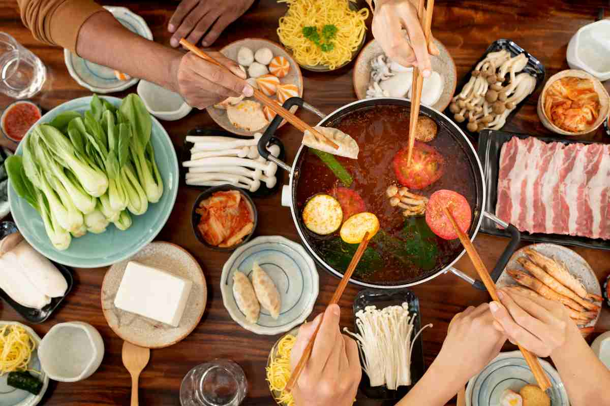 Table full of food with hotpot in the middle