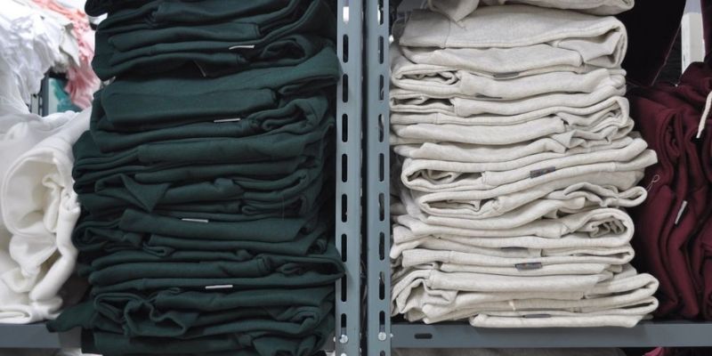 A bunch of folded clothes in the back room of clothing store