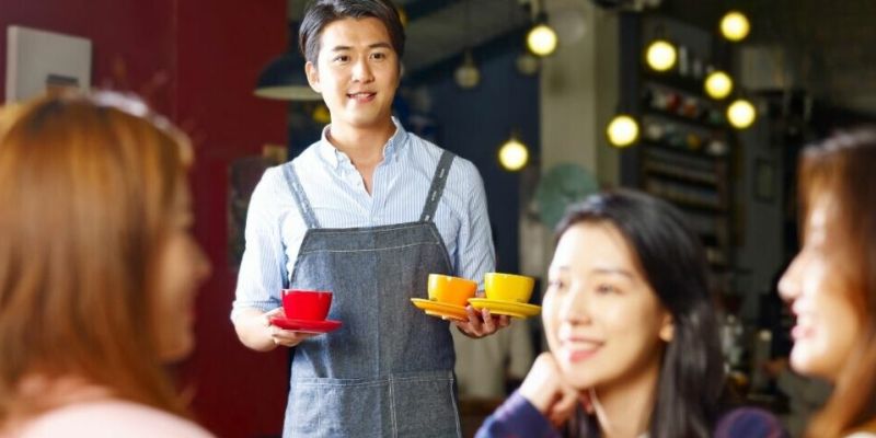 Waiter serving three cups of coffee to a table