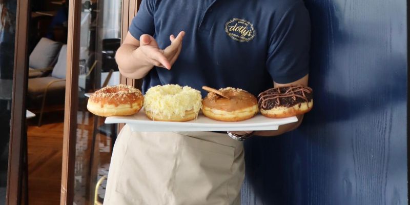 A waiter at Dotty's showcasing their range of donuts