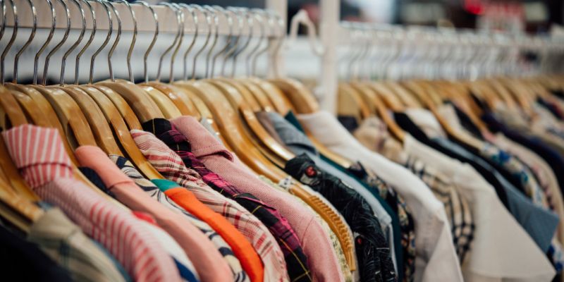 A close up shot of  bunch of clothes on a rack in a retail store