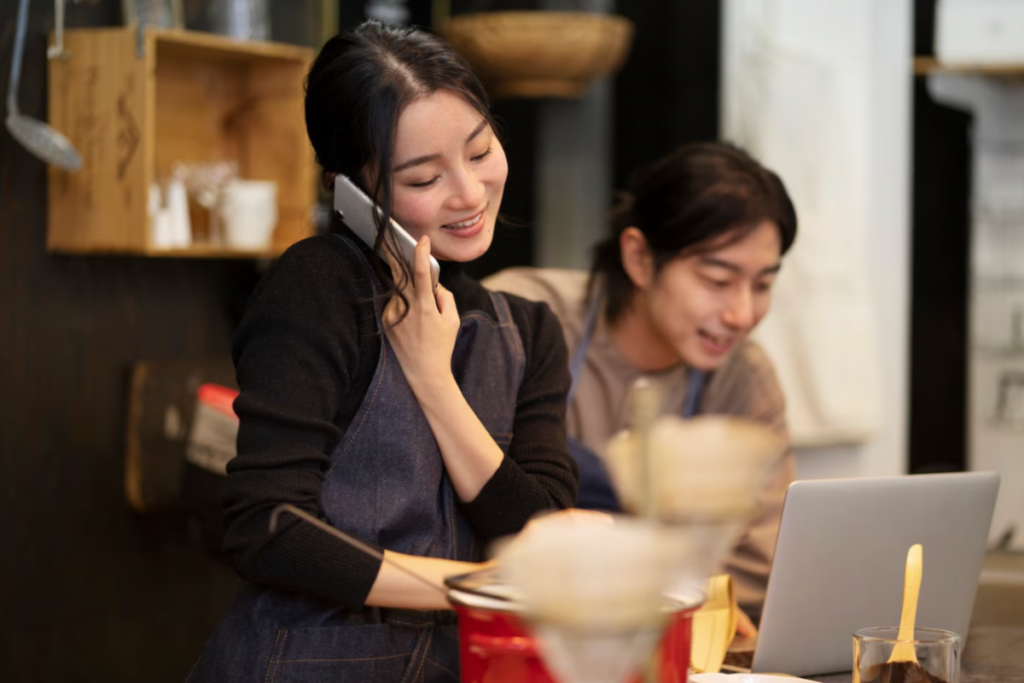 Asian business owner managing business on a laptop.