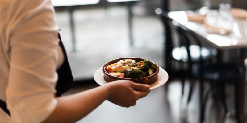 A Malaysian restaurant staff serving a plate of food to the customers