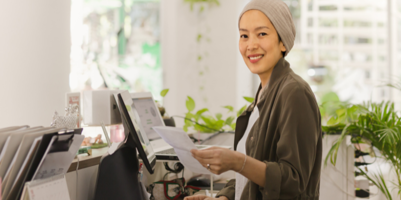 Peniaga restoran wanita yang memakai turban sedang mengemaskini status jualan sambil berdiri di hadapan sistem POS. 