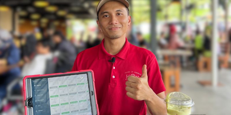 Peniaga restoran House of Kambing di MAEPS, Serdang berbaju merah kelihatan gembira dan berpuas hati dengan sistem POS StoreHub.