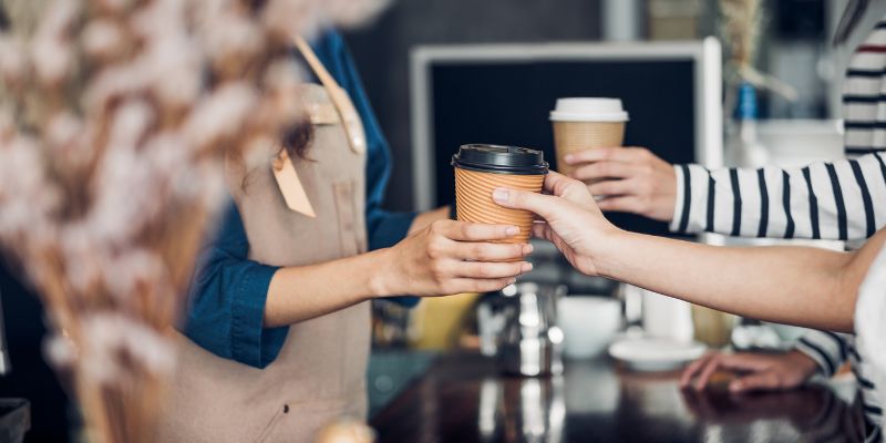 A barista handing her customer his order