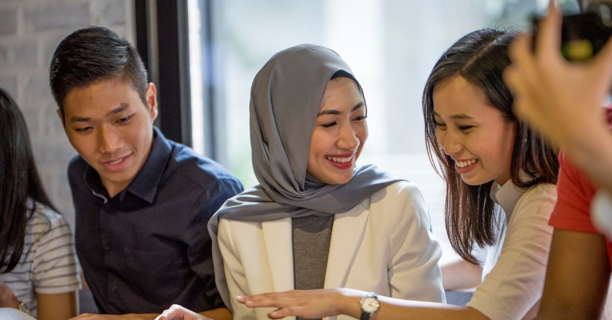 Rakan-rakan Malaysia ketawa sambil menikmati masa bersama di restoran