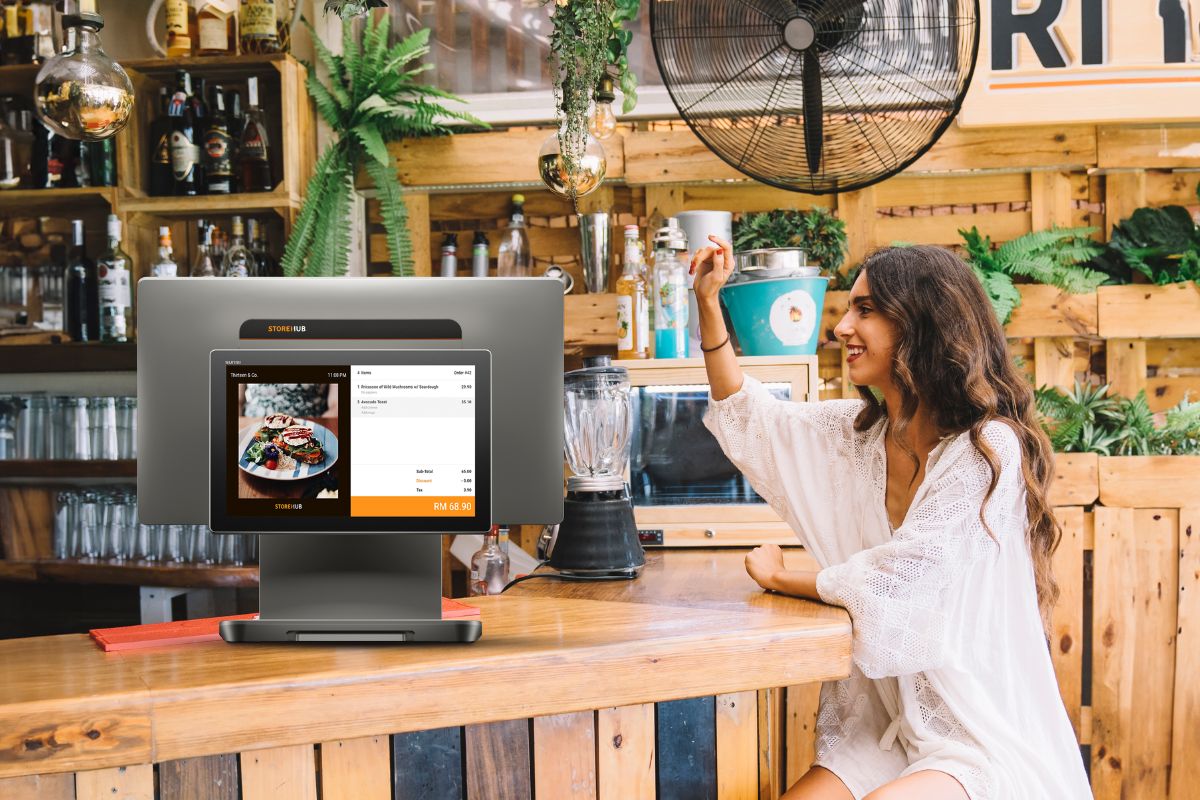 A customer at an F&B business in Klang Valley calling a waiter to place an order, with a StoreHub POS nearby
