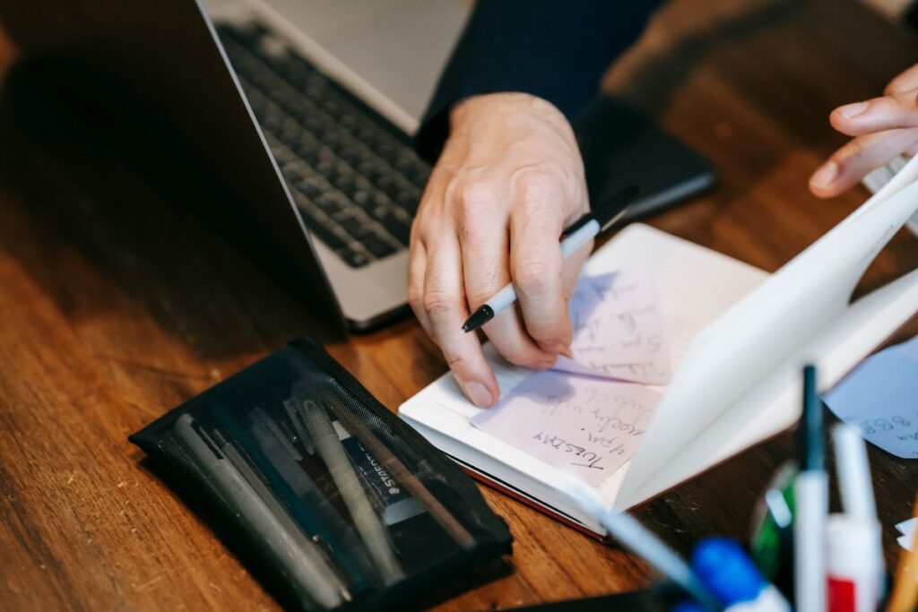 A Malaysian business owner writing on her notebook to prepare for the SST expansion