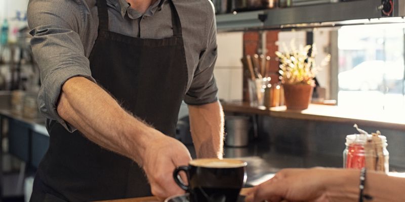 Staf F&B menghidang kopi kepada pelanggan