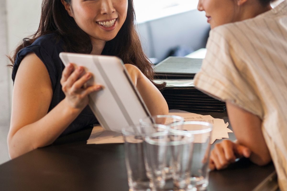 A F&B owner showing an iPad POS system to her staff