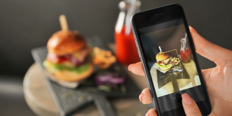 A person taking a photo of a burger