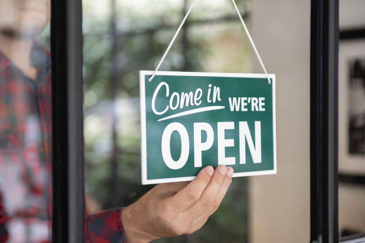 A Filipino cafe owner with an Open/Closed sign