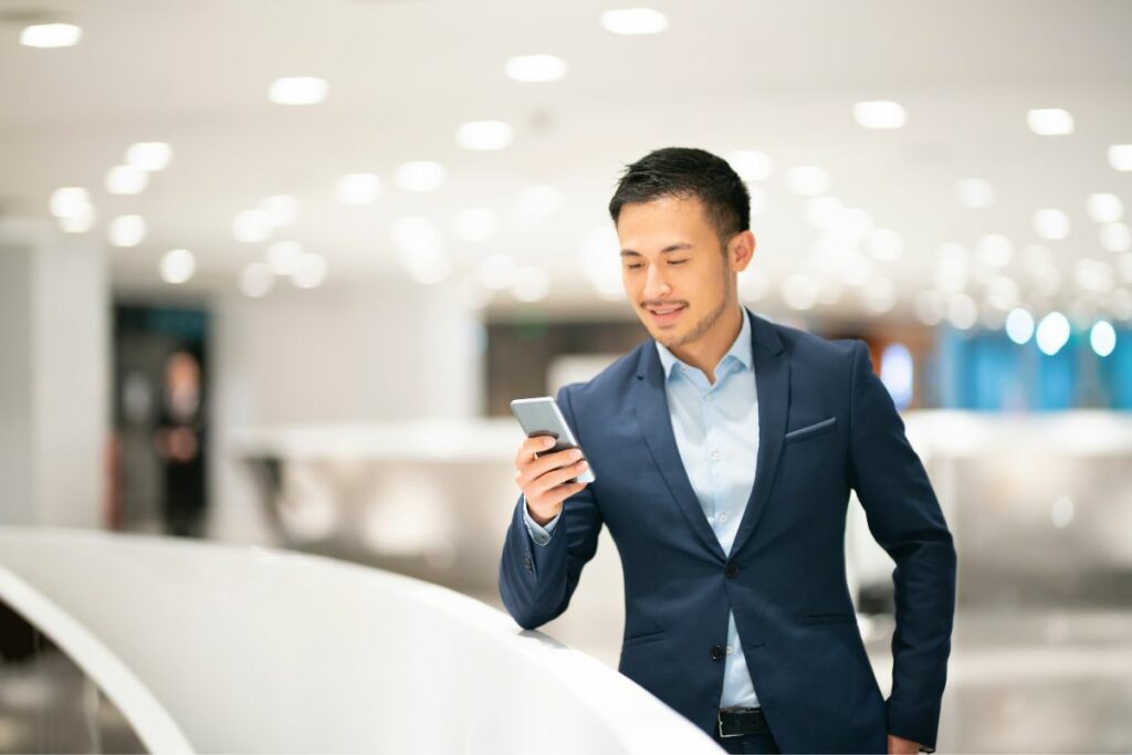 businessman smiling because he's managing his business using his phone