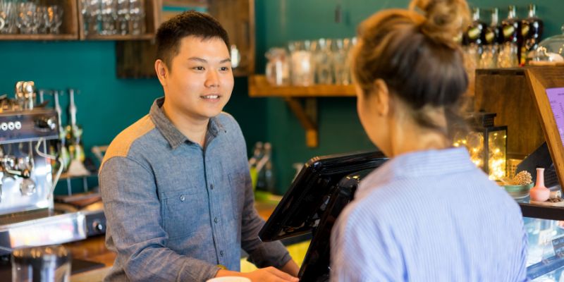  A man in a grey shirt is ready to take a customer's order at the counter using the StoreHub POS system.