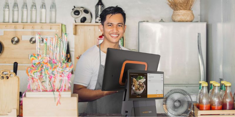 An F&B male cashier is standing in front of the StoreHub POS at the counter, ready to take customers’ orders. 