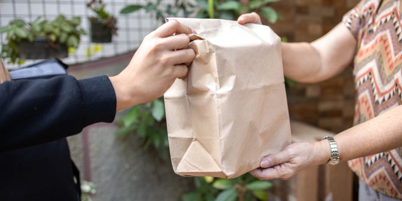 A Filipino food delivery driver handing over an order to a customer