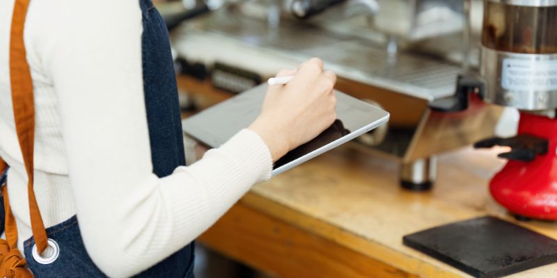 A Filipino cafe staff with a POS tablet