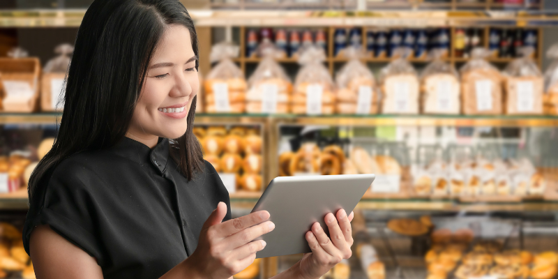 Asian business owner looking at her sales report through an iPad.