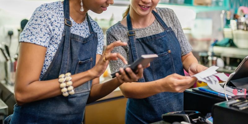 Two Filipino business owners calculating their sales in front of a POS/cash register