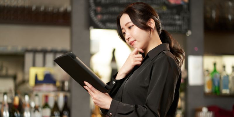 A Filipino restaurant manager looking at her tablet