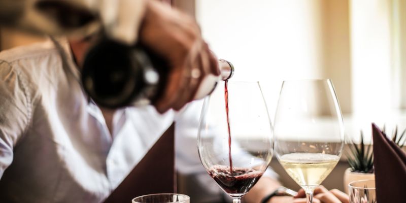 A waiter pouring wine into a glass