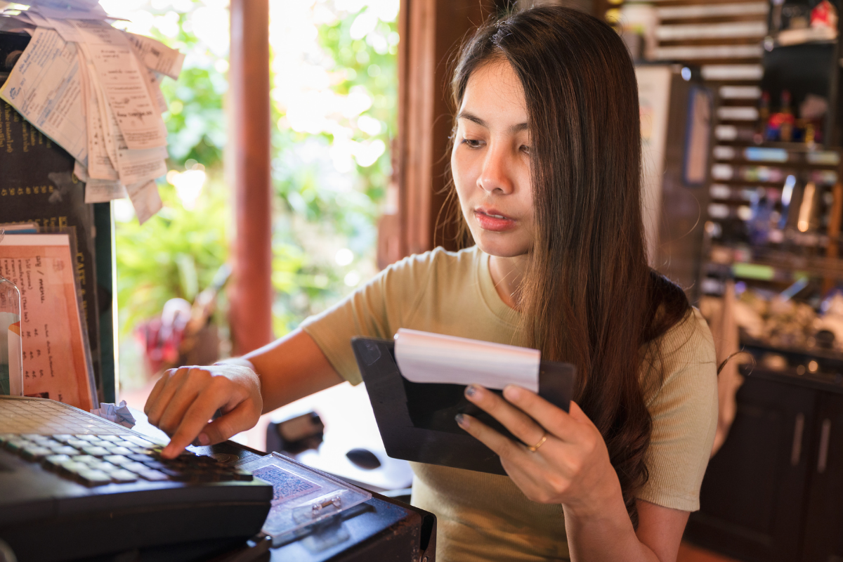 Store assistant counting up sales with an out-dated POS System.