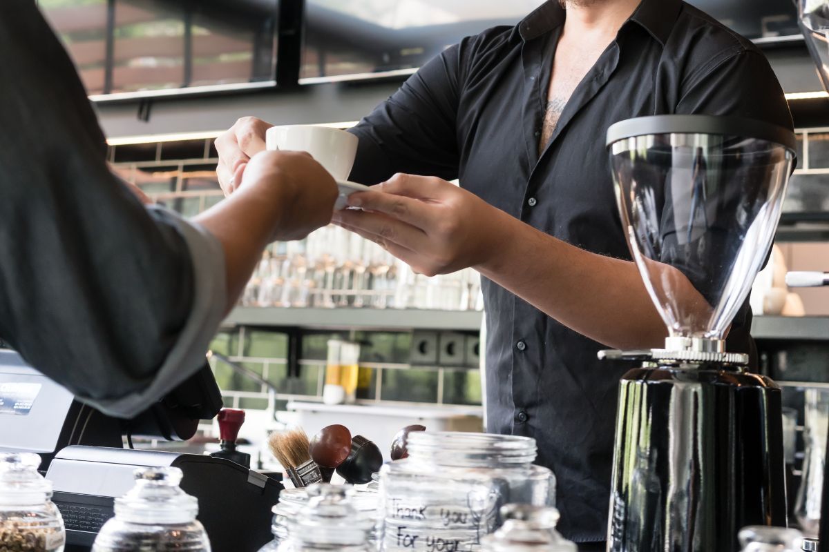 An F&B staff serving coffee to a customer