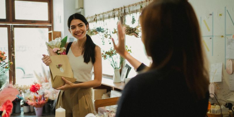 A Filipino retail owner waving goodbye to a customer