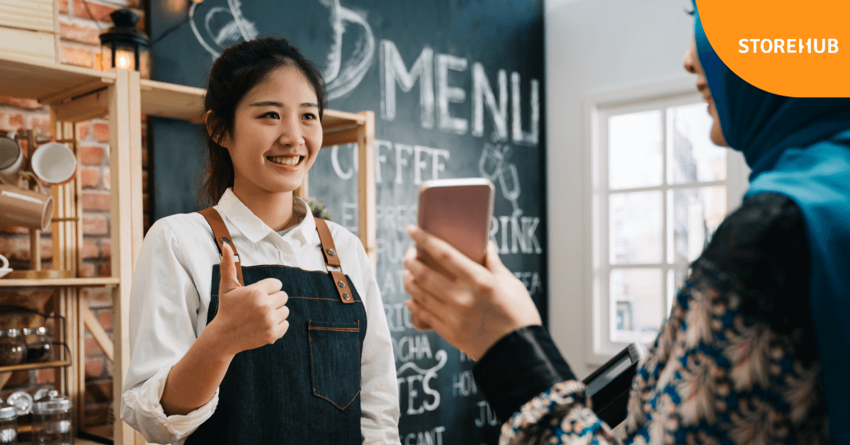 employee behind cashier with thumbs up