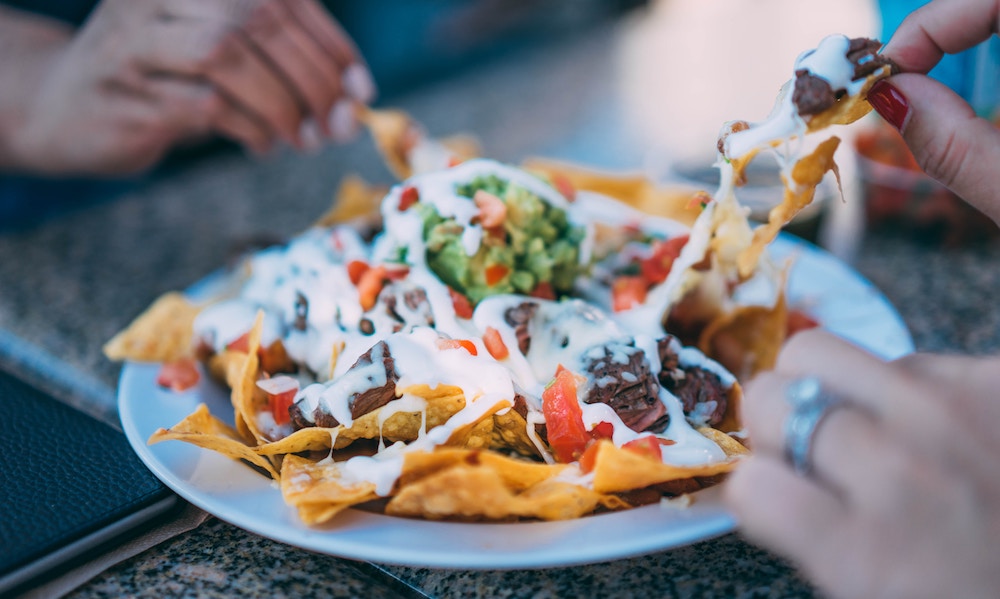 hands sharing nachos bowl for dinner