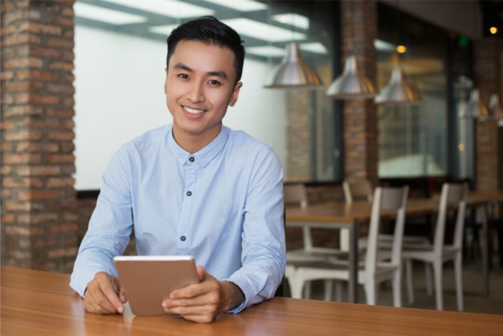 man smiling because he's running his business remotely with an iPad