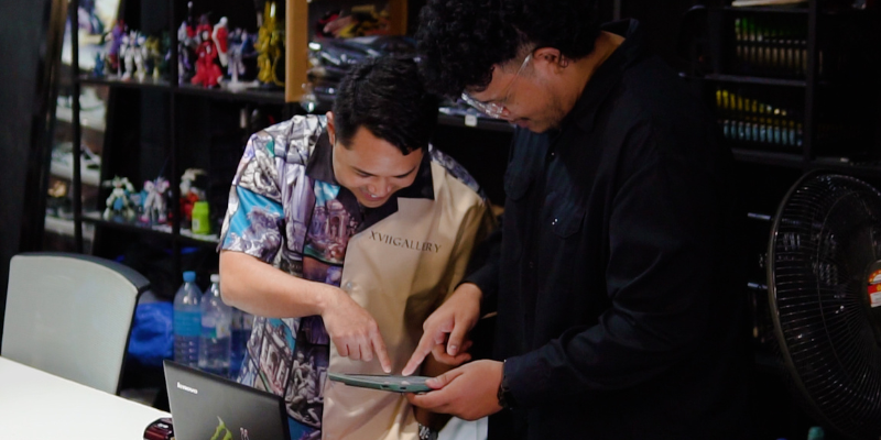 StoreHub business owner looking at business reports through a POS with his staff