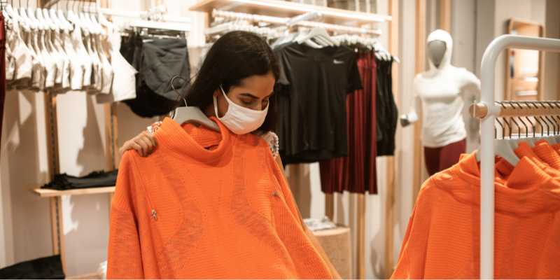 A female customer is trying on an orange top in the retail store.