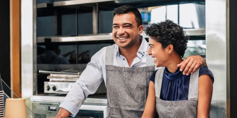 Two Malaysian business owners smiling while they’re in their restaurant